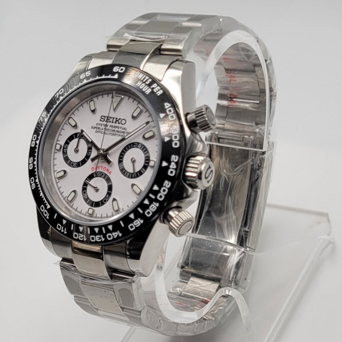 Silver Seiko watch on a clear stand against a white background