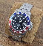 Watch with a silver bracelet on a brown cushion against a wooden background