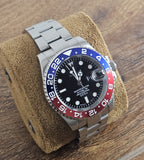 Marlin Master watch with a silver band, black face, red and blue bezel on a brown cushion.