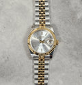 Two-tone silver and gold watch on a textured gray background