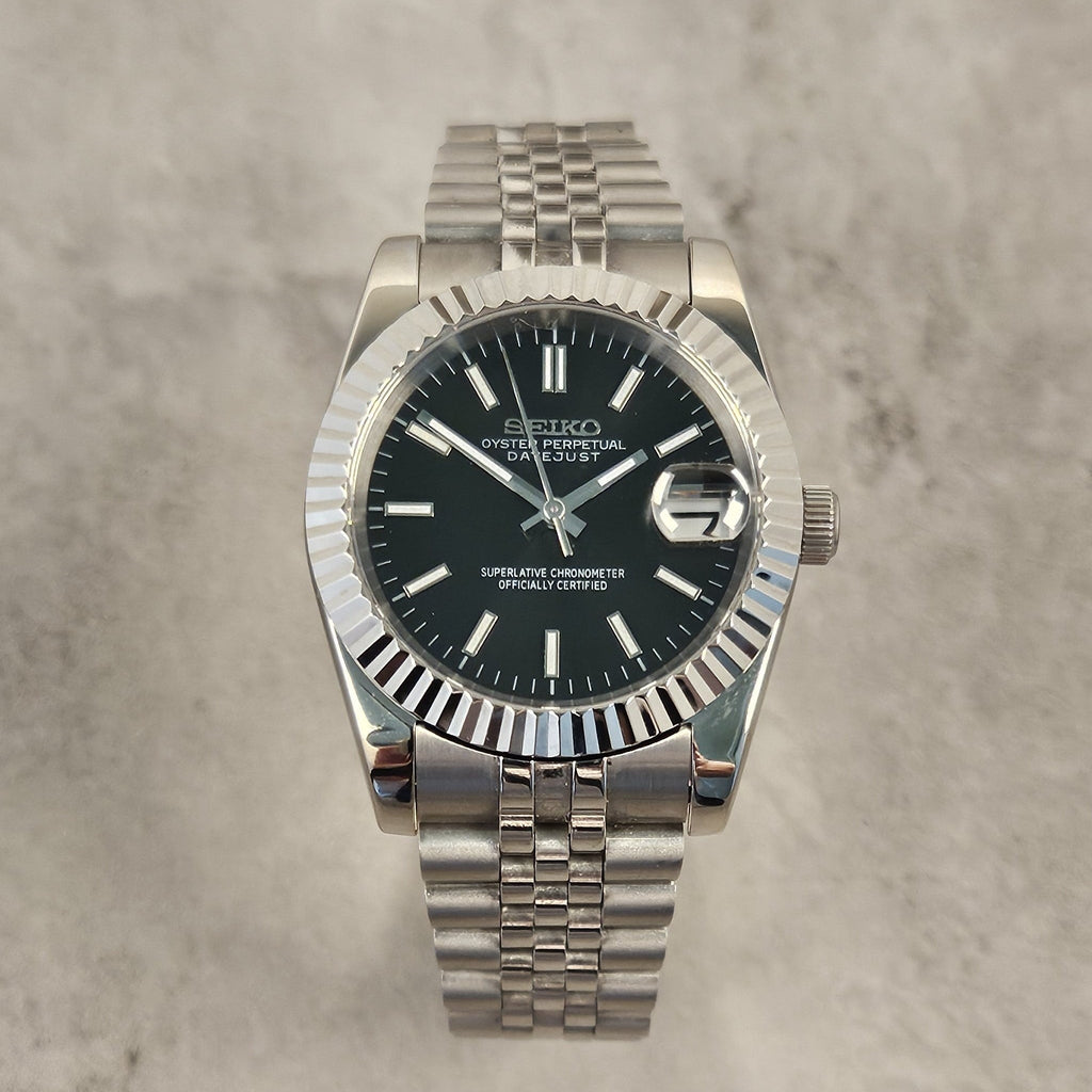 Silver Seiko watch with black dial on a gray textured background