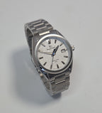 A silver stainless steel wrist watch with a textured white dial, featuring a date window, silver-tone hour markers, and a matching metal link bracelet, photographed on a light gray background.