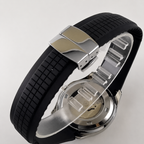 Wristwatch with black rubber strap and silver metal case on a light gray background
