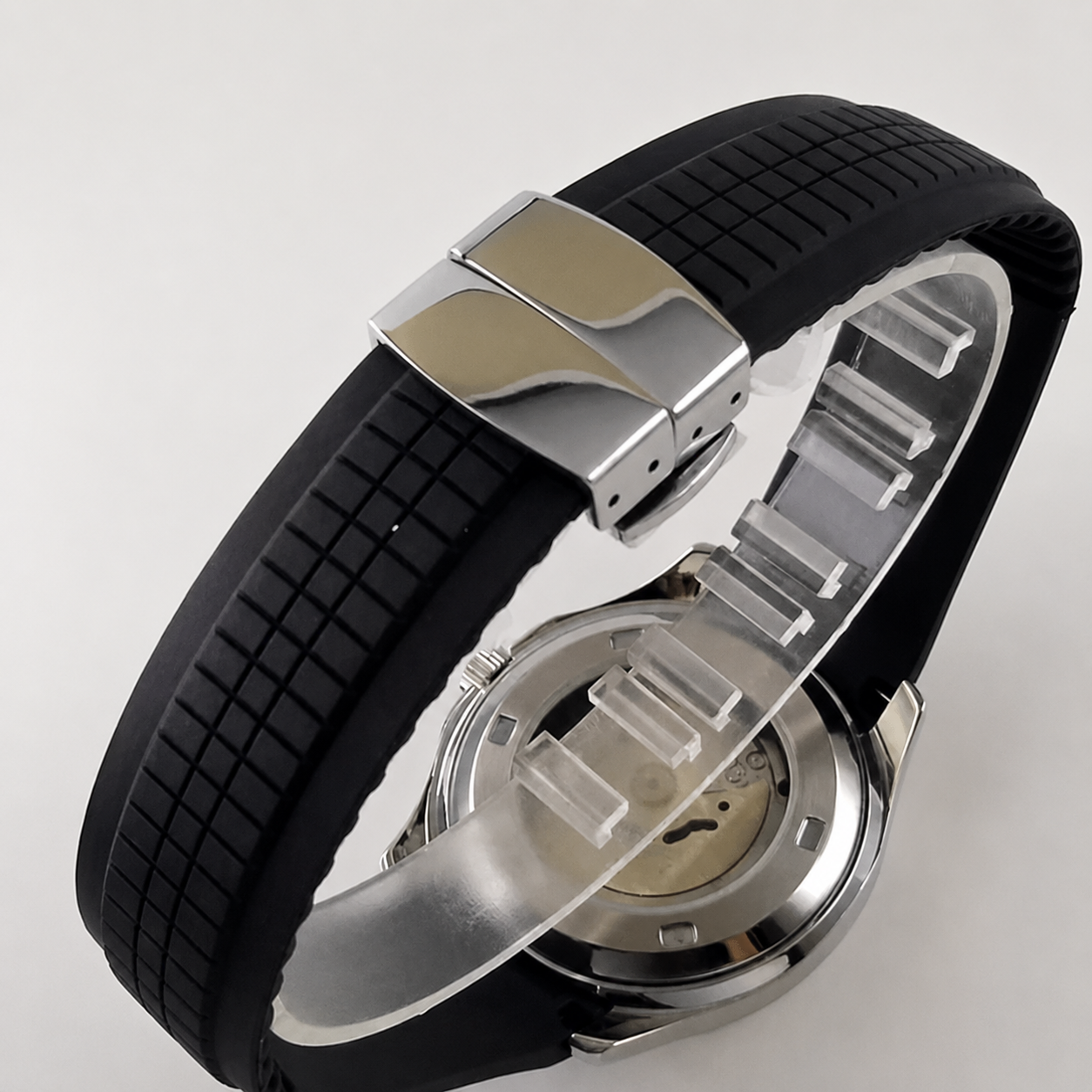 Wristwatch with black rubber strap and silver metal case on a light gray background