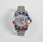 Luxury watch with a silver, blue, and red bezel on a light gray background