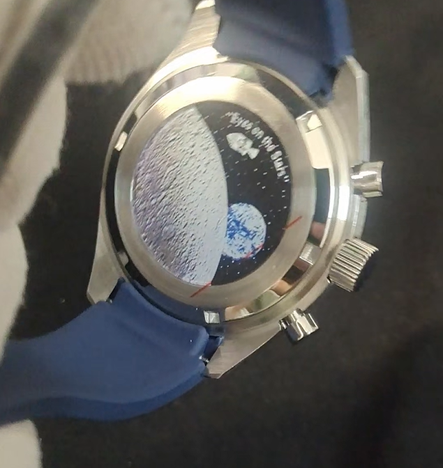 Watch with blue strap and silver case featuring a moon and Earth design