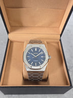 Silver watch with blue face in an open brown box on a gray surface