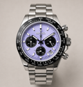 A Seiko stainless steel chronograph watch with a light purple dial, black bezel, and matching metal link bracelet, shown against a neutral beige background.