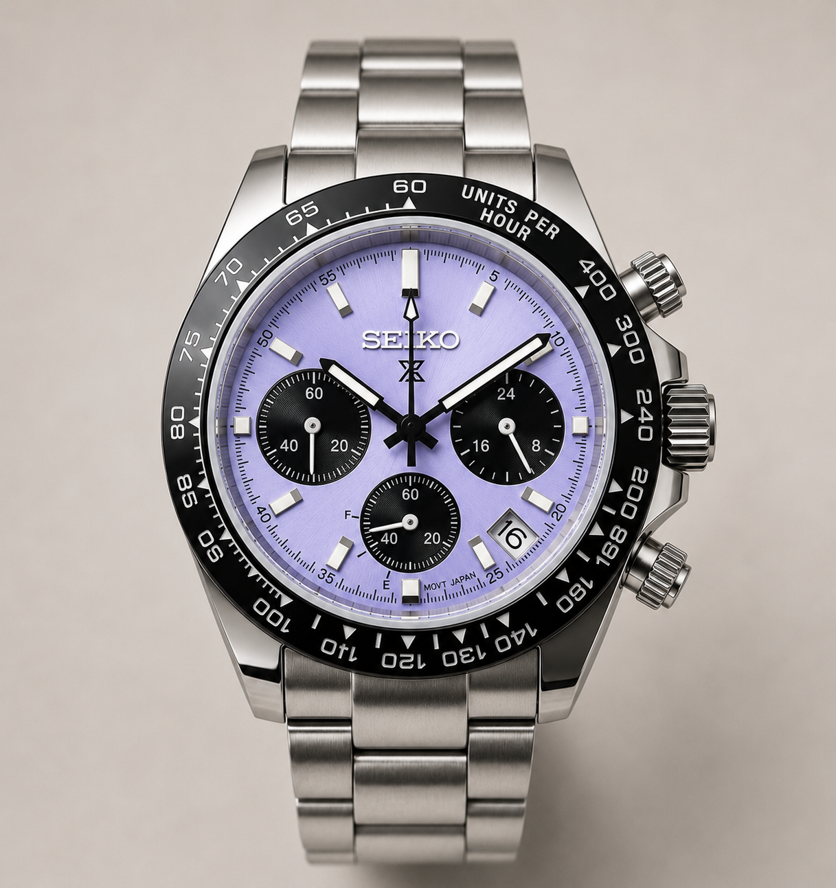 A Seiko stainless steel chronograph watch with a light purple dial, black bezel, and matching metal link bracelet, shown against a neutral beige background.