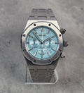 Luxury watch with a blue face and silver case on a gray background